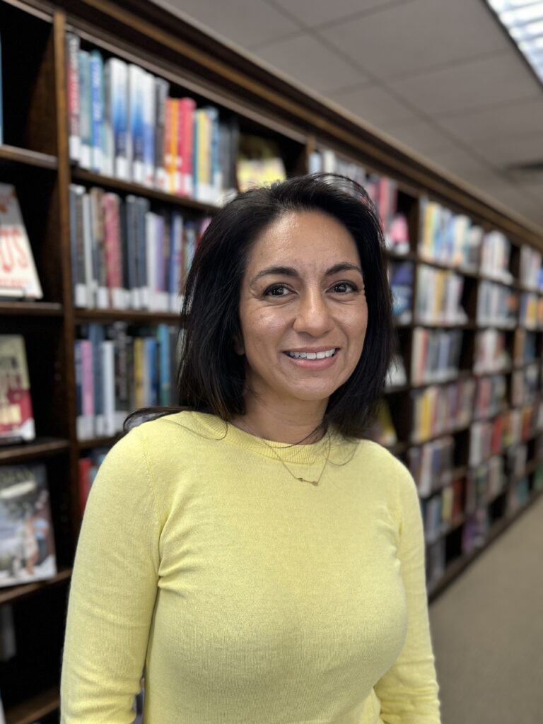 Board of Directors member Valerie Kahrs standing in front of book shelves