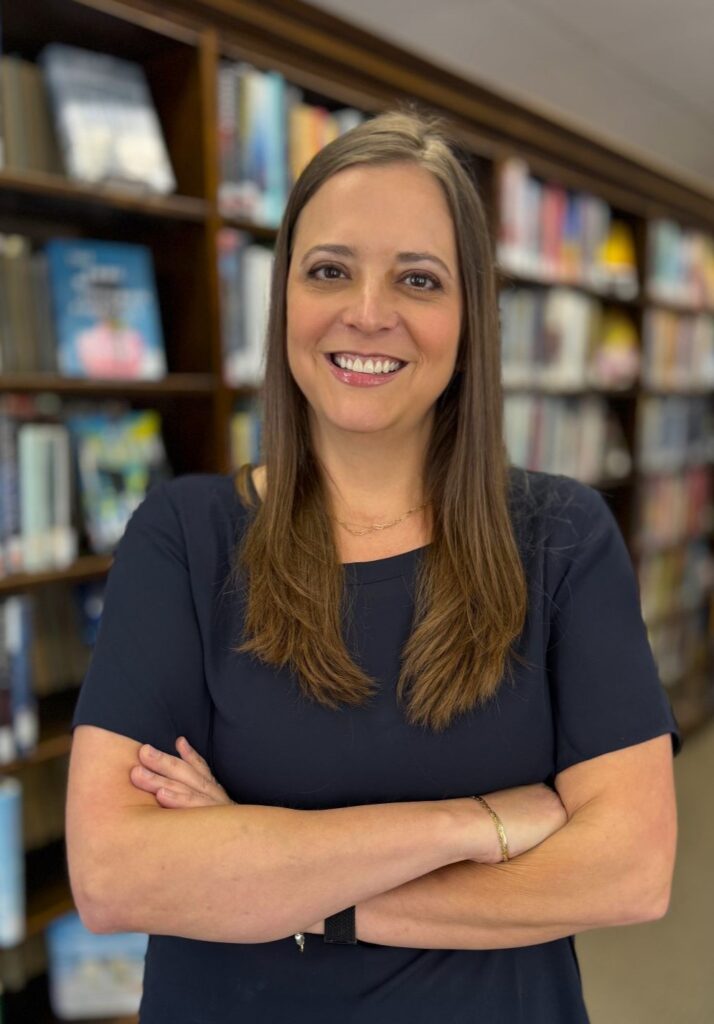 Portait of woman standing in front of book shelves wearing a blue shirt