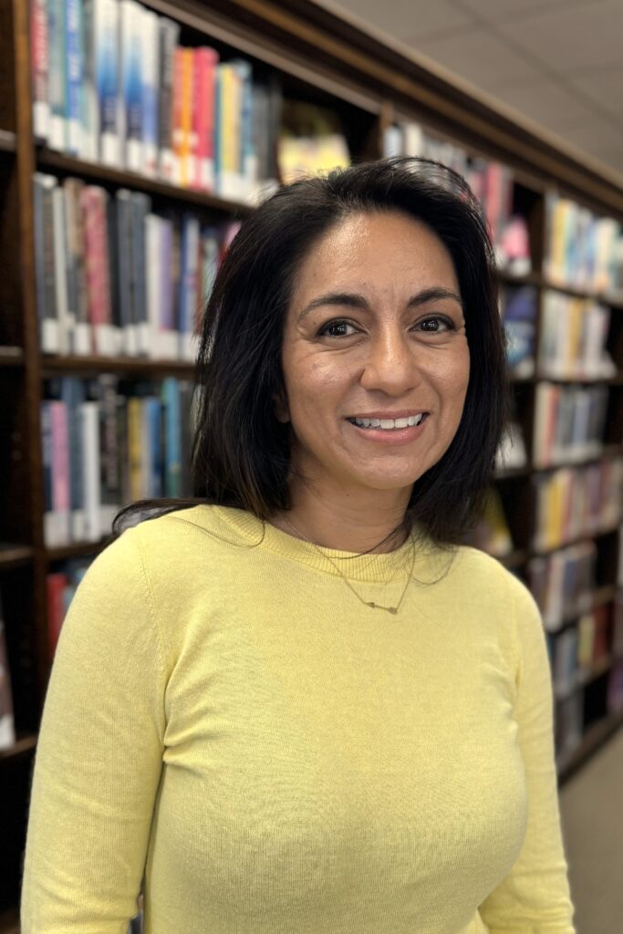 Board of Directors member Valerie Kahrs standing in front of book shelves