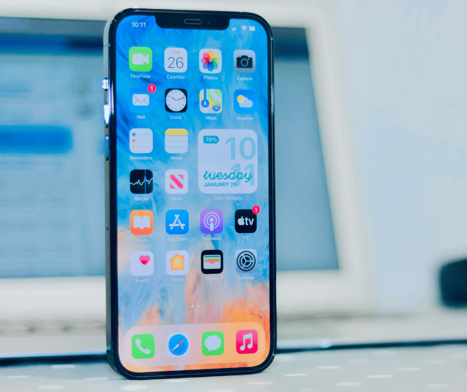 Close up view of iphone with laptop in the background
