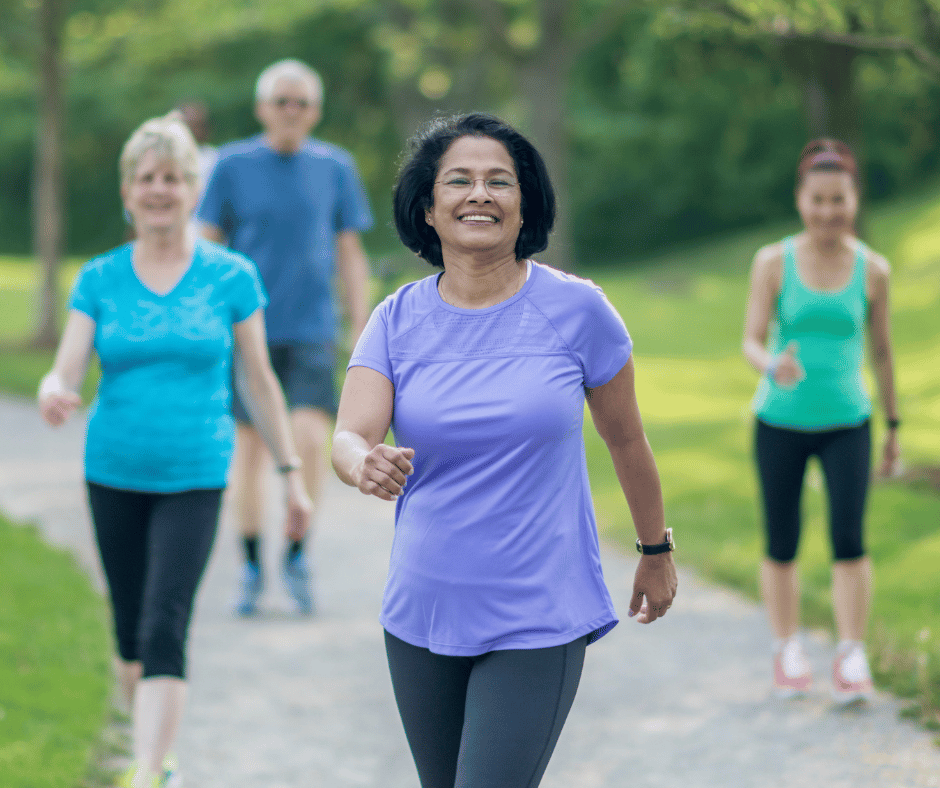 Four older adults walking outside on a sunny day